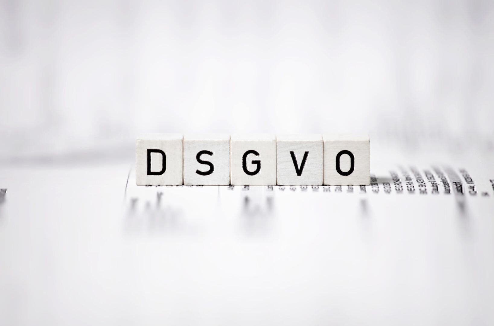 DSGVO als Buchstaben auf Würfel gedruckt liegen auf Papier